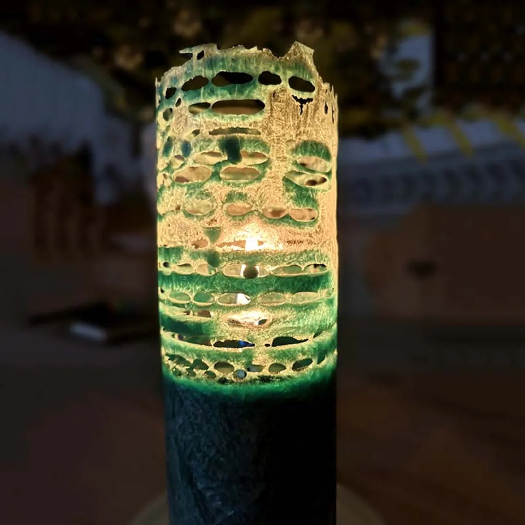 Grüne Kerze mit kunstvollem, filigranem Abbrand-Rand, der ein einzigartiges Lichtspiel erzeugt.