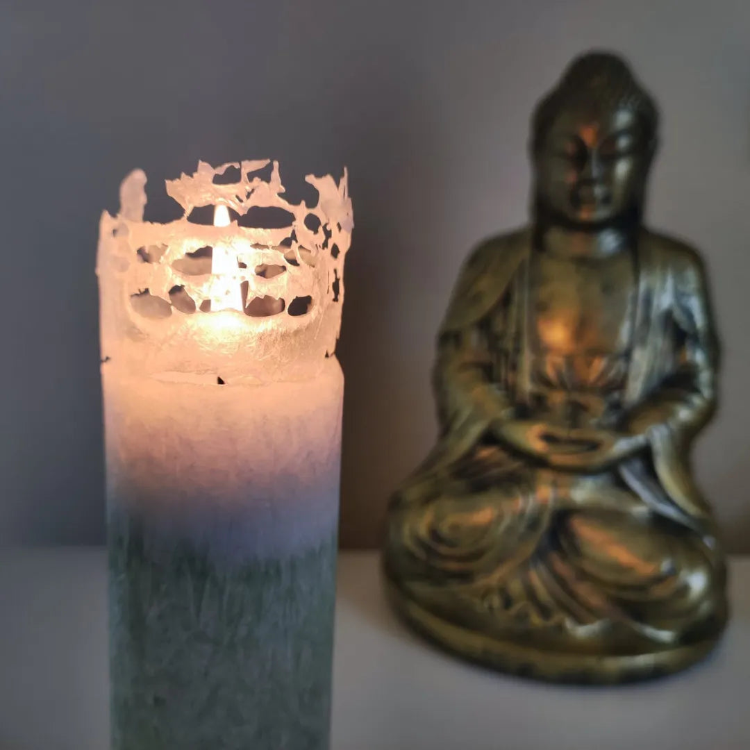Brennende Allgäuer Kräuterkerze "Zuversicht" mit Buddha-Figur, fördert innere Überzeugung & Gelassenheit.