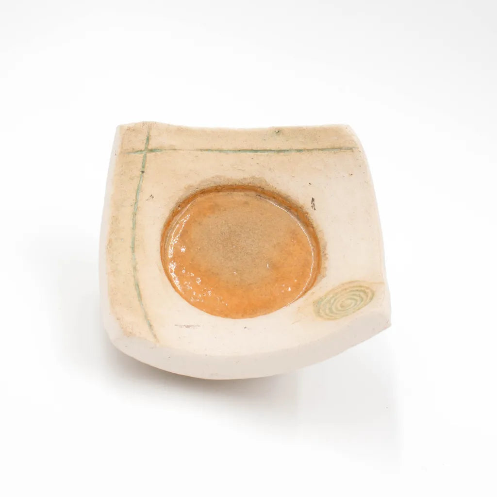 Handgetöpferter Kerzenteller mit orange-roter Mitte, Spiral- und Linienverzierung, von oben.