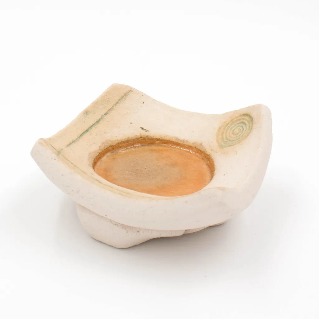 Handgetöpferter Kerzenteller mit orange-roter Mitte, Spiral- und Linienverzierung, Seitenansicht.