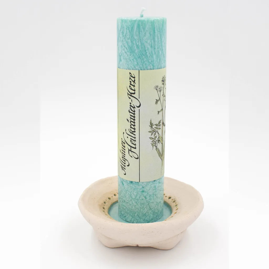 Helltürkise Allgäuer Heilkräuterkerze auf handgetöpfertem Kerzenteller mit türkis-farbener Glasur und Lochprägung.