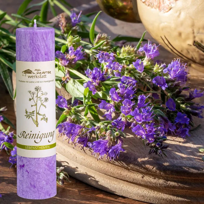Violette Kräuterkerze "Reinigung" neben frischen Blüten, ideal für energetische Hausreinigung & mentalen Neustart.