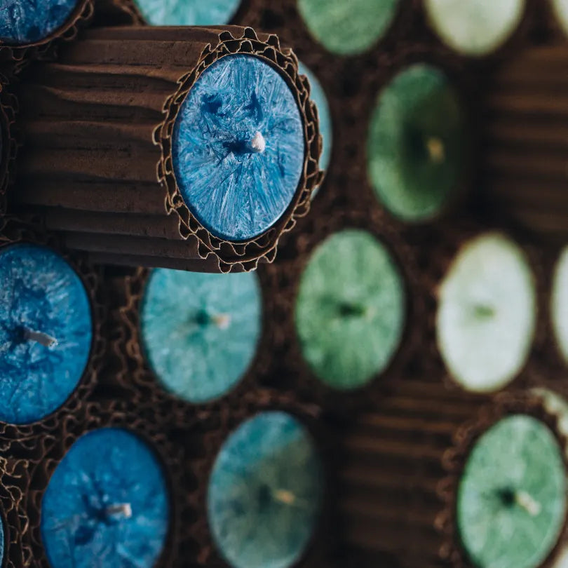 Nahaufnahme einer blauen Allgäuer Heilkräuterkerze im Karton, zeigt Docht und raue Wachs-Textur.