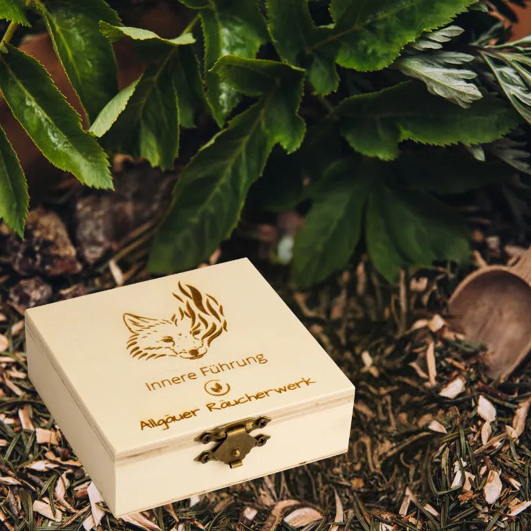 Holzbox "Allgäuer Räucherwerk Innere Führung" mit Fuchs-Motiv auf einem Bett aus Kräutern.