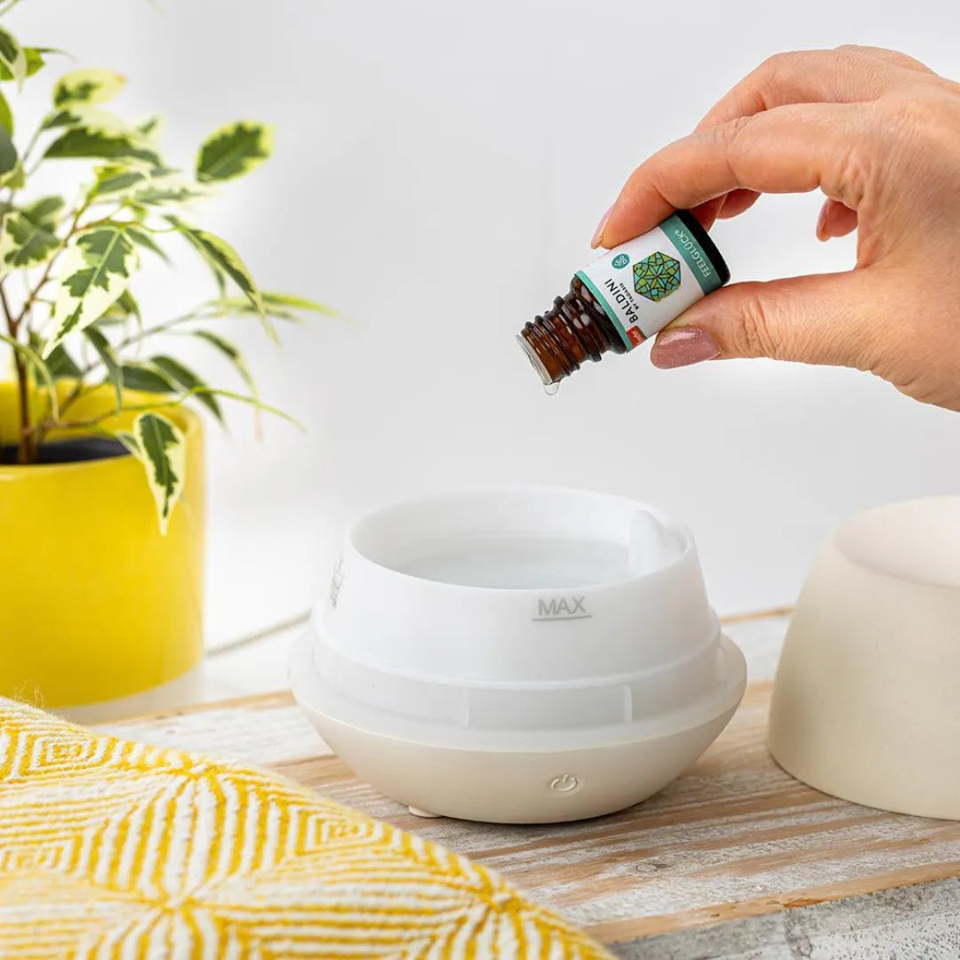 Hand tropft Baldini Feelglück ätherisches Öl in Diffuser, für Glücksduft und Wohlbefinden.