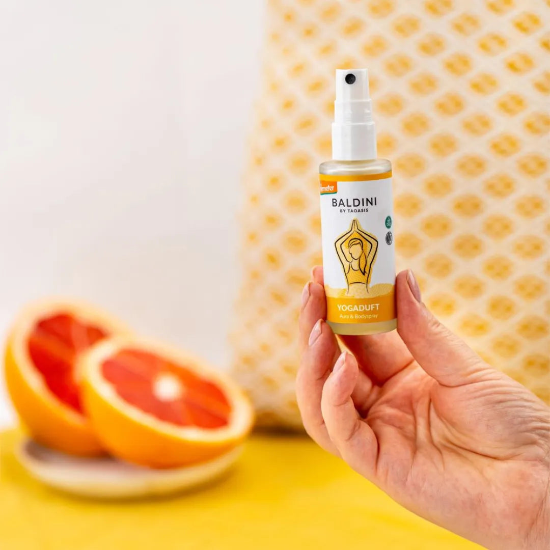Hand hält Baldini Yogaduft Aura & Bodyspray, unterstützt Yoga und Meditation, mit Grapefruit.