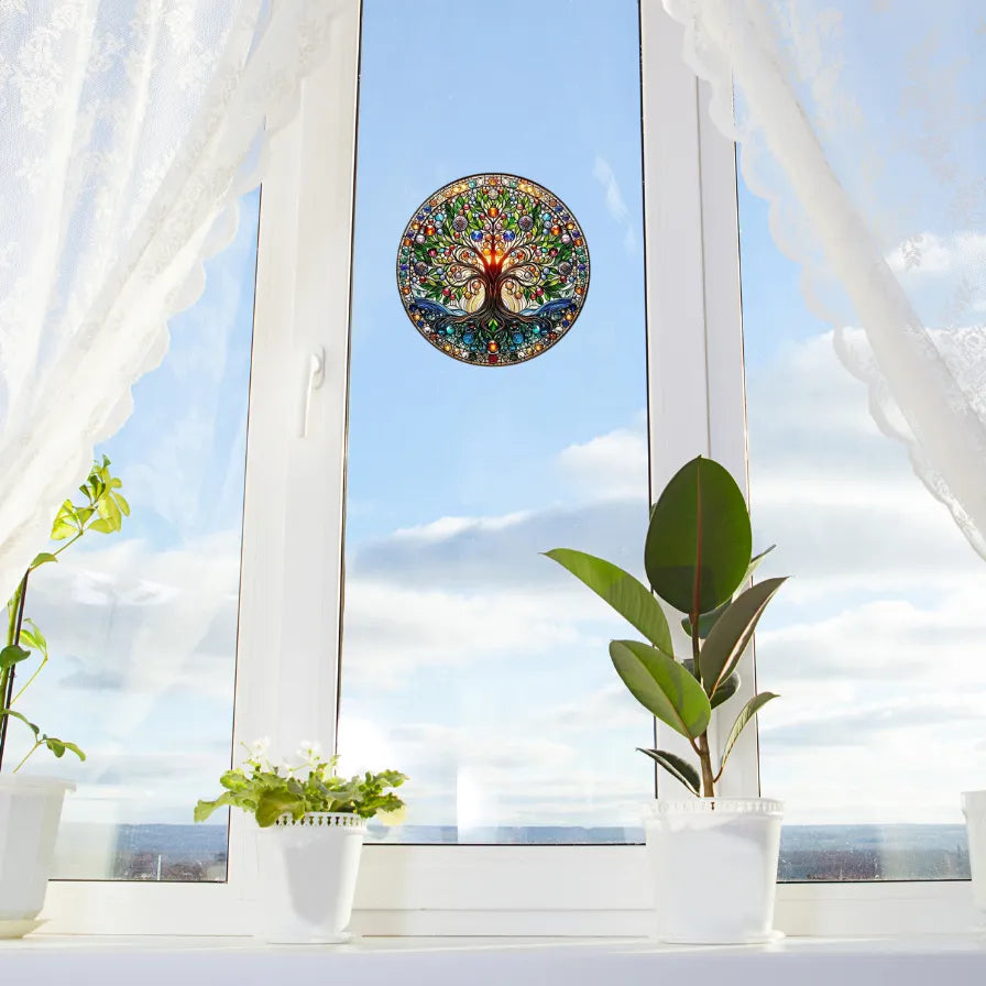 Runder Baum des Lebens Fensteraufkleber als Sonnenfänger auf hellem Fenster mit Pflanzen auf der Fensterbank, für harmonische Raumgestaltung.