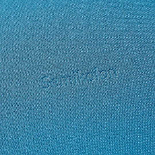 Detailansicht des azurblauen Semikolon Notizbuchs A5 mit geprägtem 'Semikolon' Schriftzug.