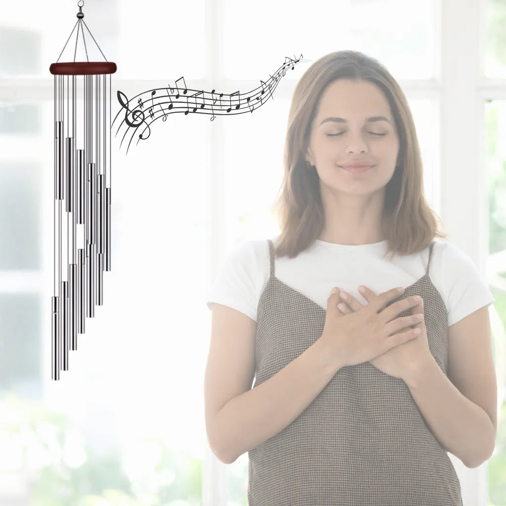 Windspiel mit spiralförmigen Röhren und Notenlinien, symbolisiert Ruhe und Entspannung bei meditierender Frau.