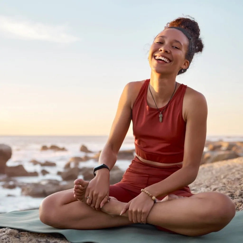 Frau meditiert am Meer, symbolisiert Achtsamkeit, innere Ruhe & spirituelle Entwicklung durch Buddhismus.