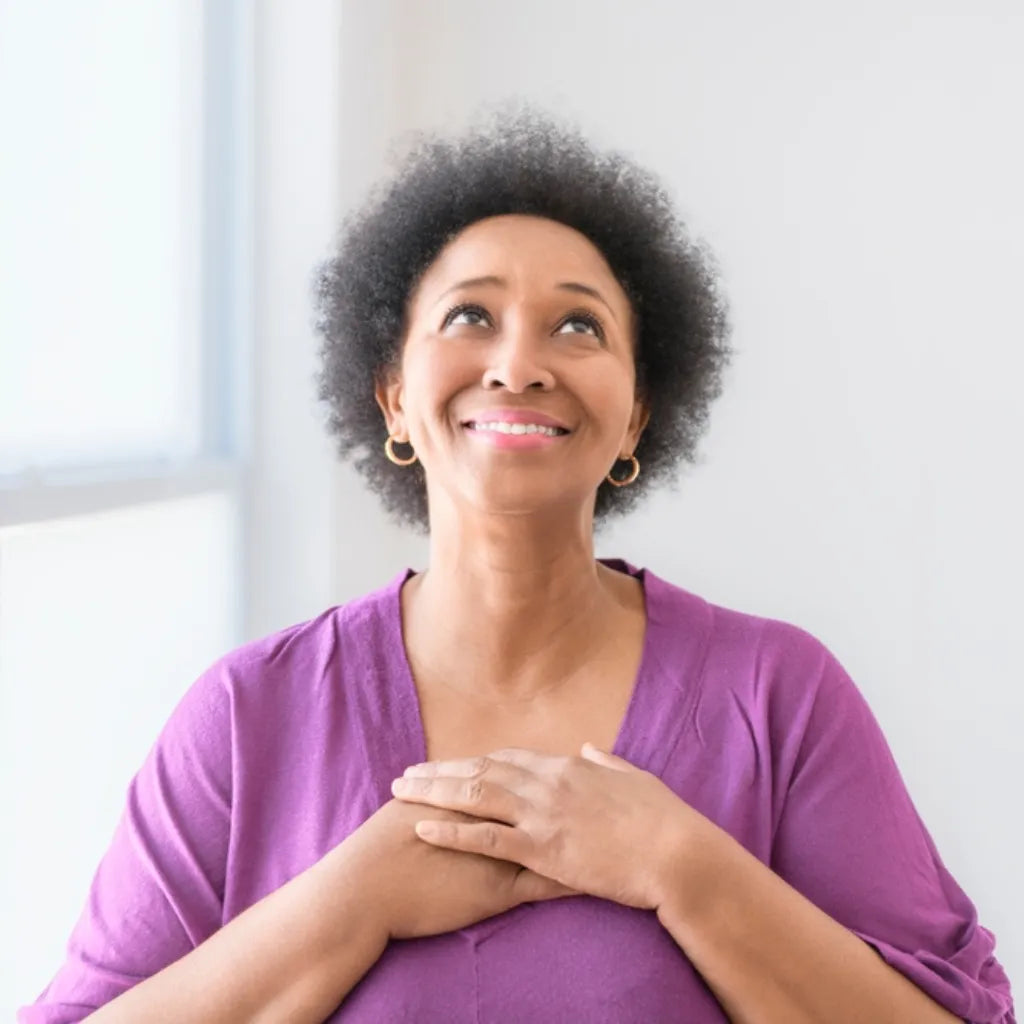 Frau mit Händen auf Brust blickt hoffnungsvoll, symbolisiert Heilung, Frieden und Erneuerung.