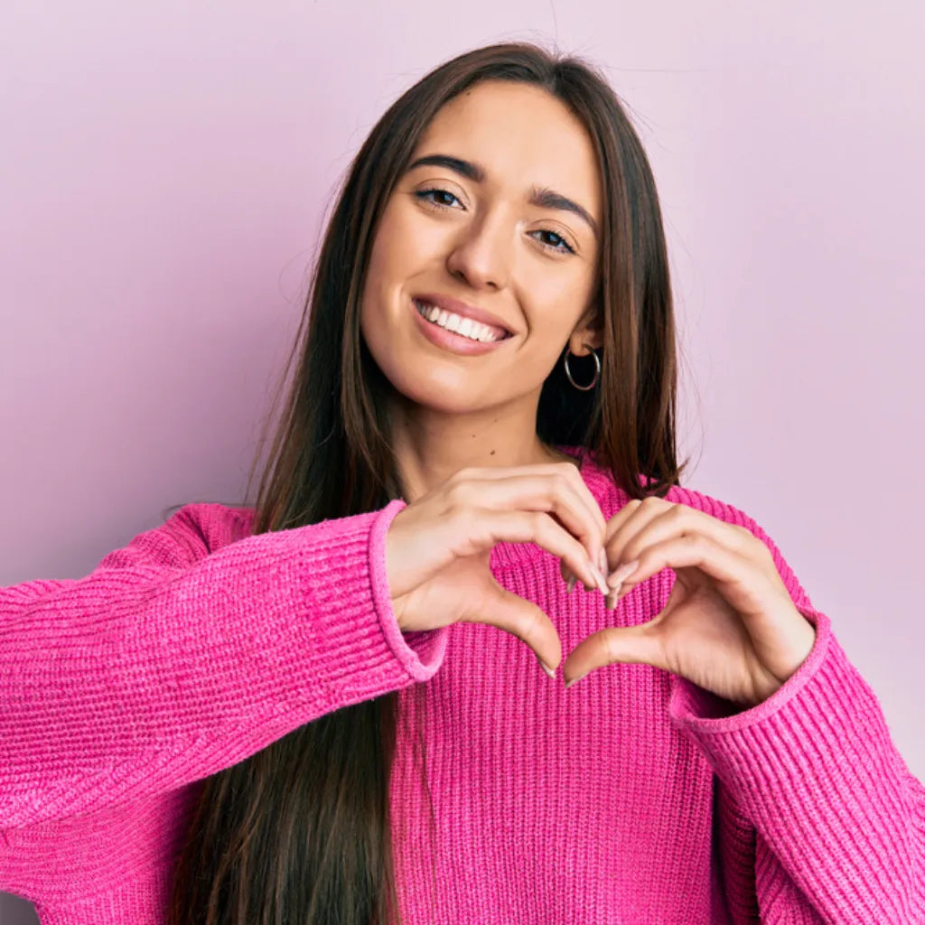 Frau formt Herz mit Händen, symbolisiert Selbstliebe, Herzensverbindung und innere Stimme.