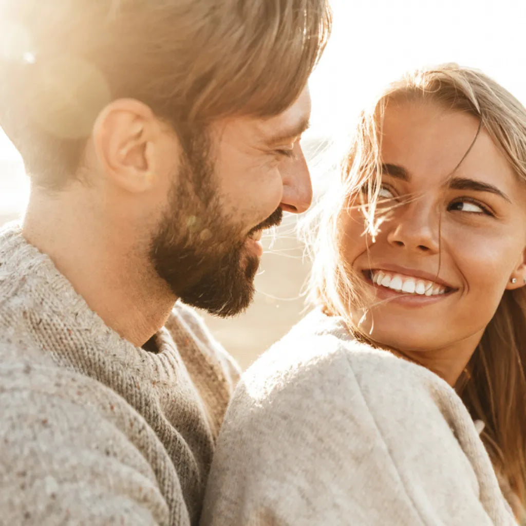 Paar lächelt sich an, symbolisiert Liebe, Vertrauen & Entspannung für den Kinderwunsch.