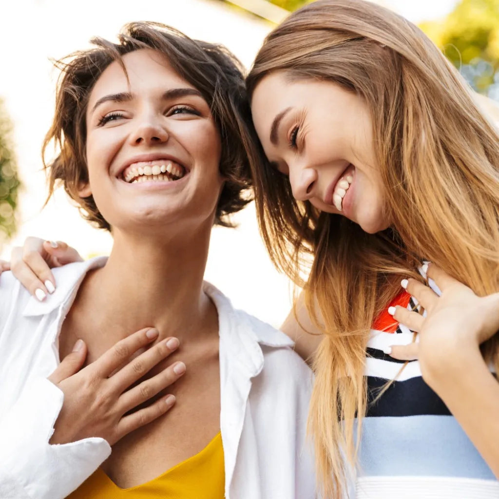 Zwei Frauen lachen herzlich, symbolisieren Freude, positives Lebensgefühl & innere Stärke durch Affirmationen.