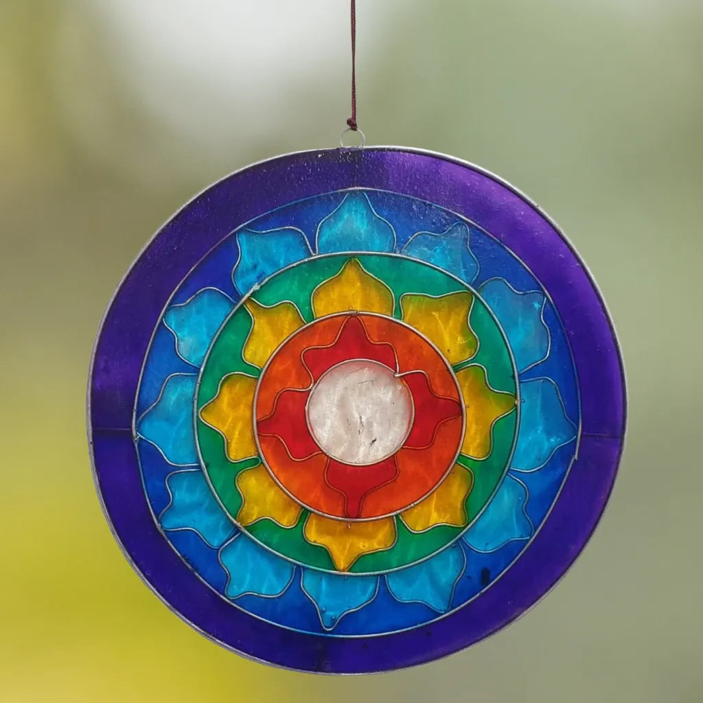 Der Sonnenfänger "Lotus Chakra Regenbogen" aus buntem Glas hängt vor einem weichen, unscharfen Hintergrund. Erzeugt ein wunderschönes Lichtspiel und positive Atmosphäre in jedem Raum.