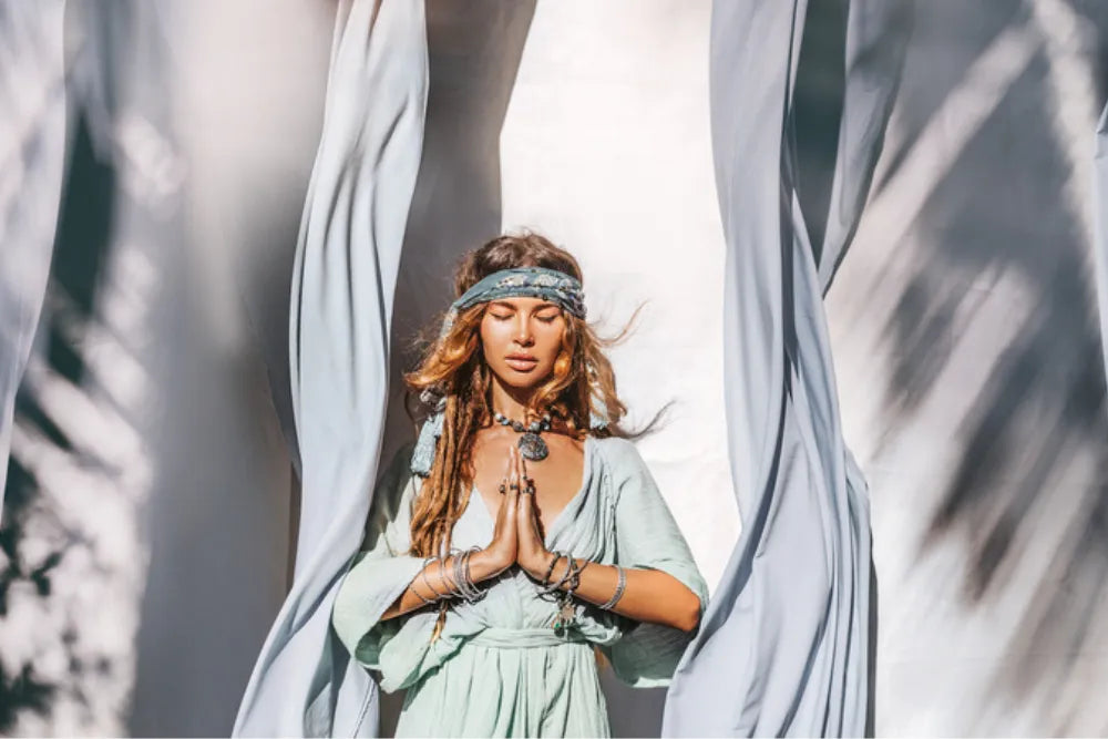 Frau in meditativer Pose mit geschlossenen Augen und betenden Händen, symbolisiert Spiritualität.