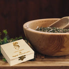 Holzbox "Allgäuer Räucherwerk Lebendigkeit" mit Eichhörnchen-Motiv neben Kräuterschale.