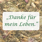Affirmation "Danke für mein Leben" auf Hintergrund aus Kräutern der Räuchermischung.