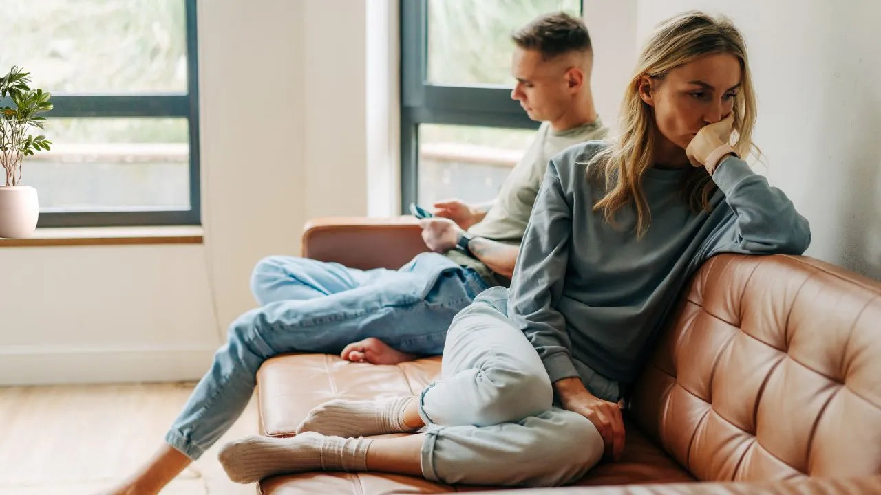 Ein Paar sitzt abgewandt von einander auf der Couch, die Stimmung ist sehr angespannt.