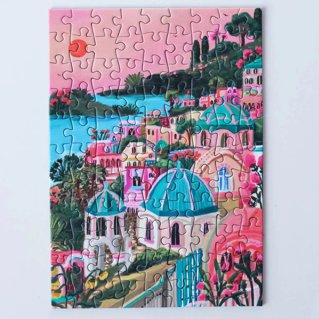 Das komplett gelegte 99 Teile Piecely Minipuzzle "Santorini Sun". Präsentiert eine leuchtende Szene mit rosa Himmel, weiß getünchten Häusern und blauen Kuppeln am Meer der griechischen Insel.