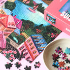 Ein begonnenes Piecely Puzzle 500 "Suisse Nights" mit lose liegenden Puzzleteilen und einer kleinen Schale voller weiterer Teile. Zeigt den Prozess des Puzzelns mit dem Motiv der Schweizer Nacht.