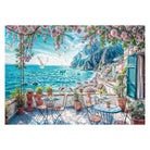 Detailliertes Motiv des Schmidt Puzzles 1000 Teile "Terrasse am Meer". Ein sonniger Balkon mit Tischen, blühenden Pflanzen und Blick auf das blaue Mittelmeer und Küstenstadt.