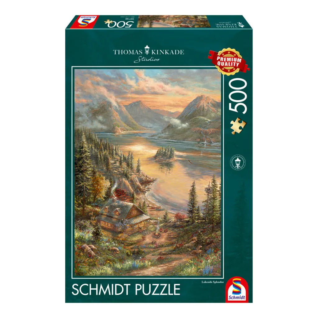 Schmidt Puzzle 500 Teile "Pracht am Seeufer" von Thomas Kinkade. Produktverpackung mit idyllischer Seeuferlandschaft, gemütlicher Hütte, Bergen und goldener Abendstimmung. Premium Qualität.