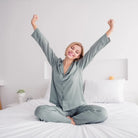 Frau streckt sich erholt im Bett, symbolisiert erholsamen Schlaf & Entspannung durch Einschlafmeditation.